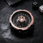 Rose gold and black metal D20 decision spinner rotating on a black leather tabletop.