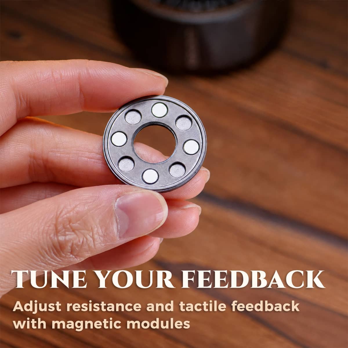 Hand holding a circular magnetic module used to adjust spinner resistance and tactile feedback.