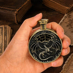 Hand holding an antique bronze pocket press dice with dragon relief and number selector.