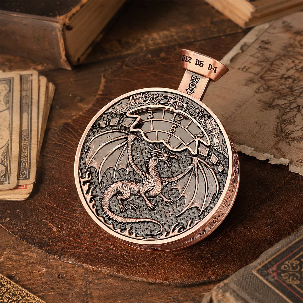 Copper pocket press dice with raised dragon relief displayed beside cards and books.