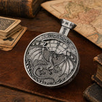 Silver pocket press dice with raised dragon relief displayed on a fantasy tabletop.