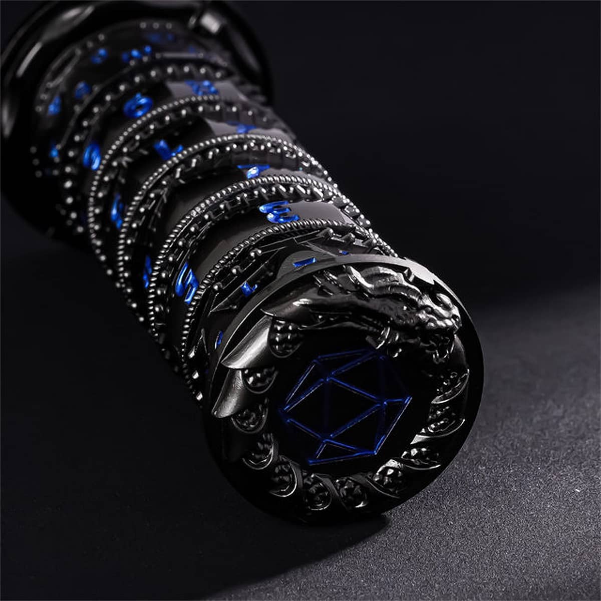 Black and blue 7-in-1 spinner dice laid horizontally with sculpted dragon end cap.