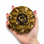 Hand holding an antique gold circular 7-in-1 RPG dice spinner with dragon relief.