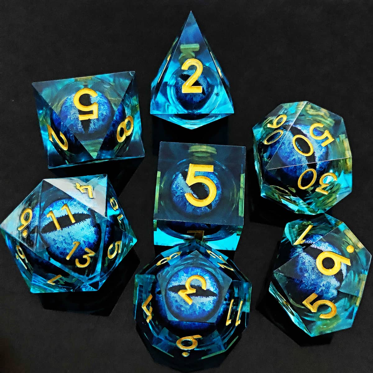 Blue moving dragon eye polyhedral dice set with gold numbers on a black background.