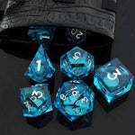 Ocean Blue liquid-core RPG dice set with clear blue resin and white numbers beside a dice bag.