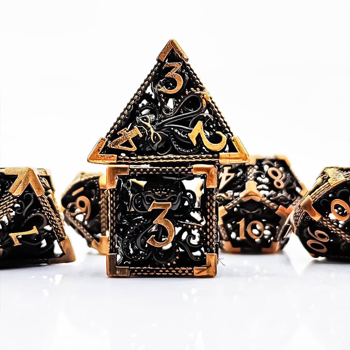 Antique gold Abyssal hollow metal RPG dice set with gothic tentacle openwork on white.
