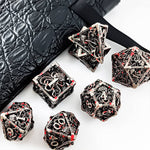 Silver hollow metal RPG dice set with red accents arranged beside a black dice bag.