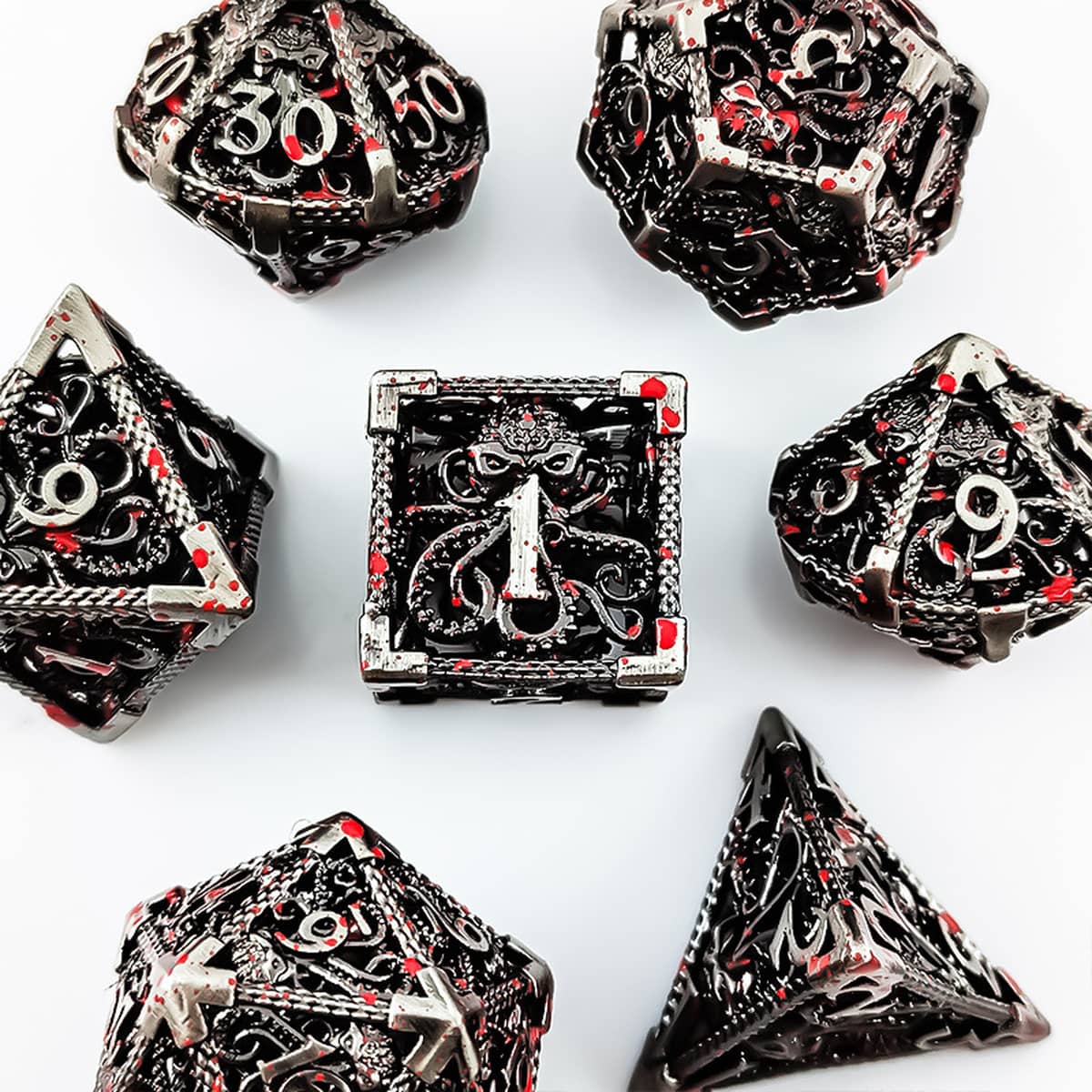 Top view of the silver hollow metal RPG dice set with red splatter accents.